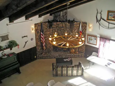 a large room with a stone wall with a chandelier at Yosemite Lakes River Yurt 22 in Harden Flat