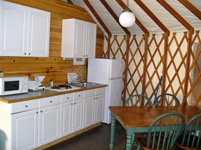 a kitchen with white cabinets and a table and a refrigerator at Yosemite Lakes River Yurt 22 in Harden Flat