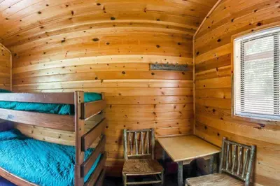 a log cabin with a bunk bed and two chairs at Yosemite Lakes Bunkhouses in Harden Flat