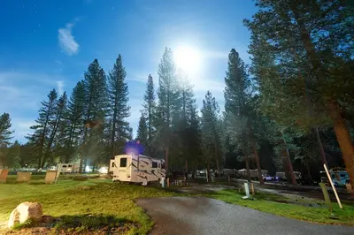 an rv parked in a field next to a forest at Yosemite Lakes Bunkhouses in Harden Flat
