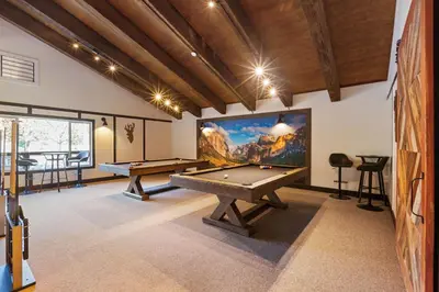 a game room with two pool tables and a large screen at Yosemite Lakes Bunkhouses in Harden Flat