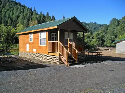 a small wooden cabin with a porch and a staircase at Yosemite Lakes Cabin 37 in Harden Flat