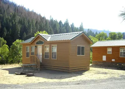 a small cabin with a metal roof and a porch at Yosemite Lakes Cottage 47 in Harden Flat