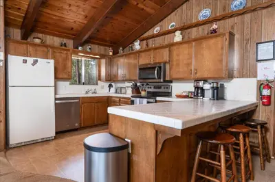 a kitchen with wooden cabinets and a white refrigerator at PaPa Bear Cabin in North Wawona