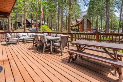 a wooden deck with picnic tables and chairs on it at PaPa Bear Cabin in North Wawona
