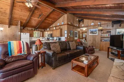 a living room with leather furniture and a kitchen at PaPa Bear Cabin in North Wawona