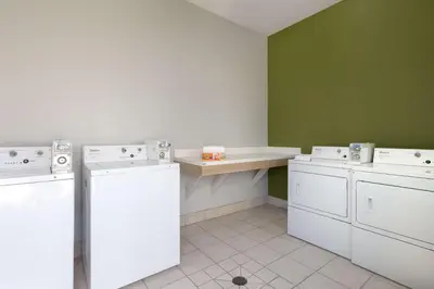 a laundry room with three washes and a counter at Spark By Hilton Santa Nella in Santa Nella Village