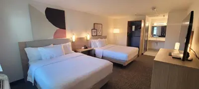 a hotel room with two beds and a desk at Spark By Hilton Santa Nella in Santa Nella Village