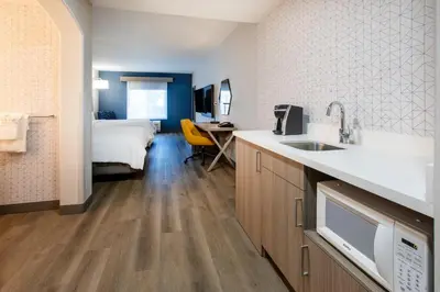 a kitchen with a sink and a bed in a room at Holiday Inn Express & Suites Lathrop by IHG in Lathrop