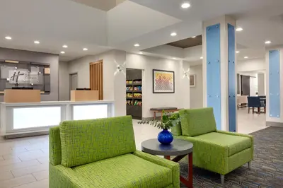 a lobby with two green chairs and a table at Holiday Inn Express & Suites Merced - Yosemite Natl Pk Area by IHG in Merced