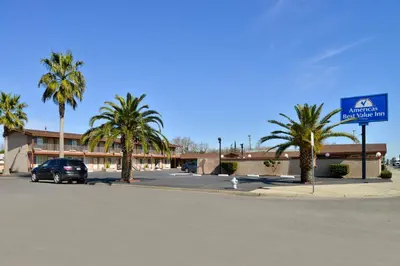 a car parked in front of a building with palm trees at Americas Best Value Inn Los Banos in Los Banos