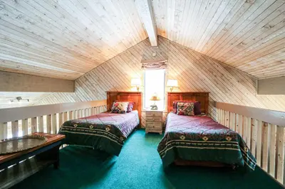 a attic room with two beds and a window at Mammoth Reservations in Mammoth Lakes