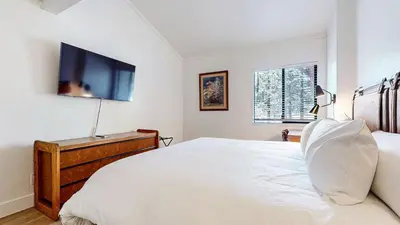 a bedroom with a white bed and a tv on the wall at Mammoth Reservations in Mammoth Lakes