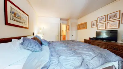 a bedroom with a large bed and a flat screen tv at Summit 45 Apartment in Mammoth Lakes