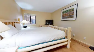 a bedroom with a white bed and a television at Summit 49 Apartment in Mammoth Lakes