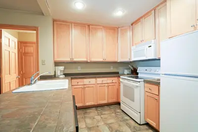 a kitchen with wooden cabinets and a white refrigerator at Summit 55 Apartment in Mammoth Lakes