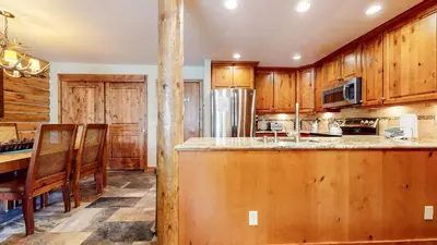 a kitchen with wooden cabinets and a table and chairs at Summit 81 Apartment in Mammoth Lakes