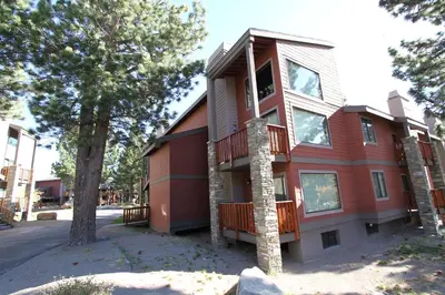 a red house with a balcony on a street at Summit 81 Apartment in Mammoth Lakes