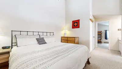 a white bedroom with a large bed and a hallway at Mammoth Reservations in Mammoth Lakes