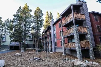 a apartment building with a balcony and trees at Mammoth Reservations in Mammoth Lakes