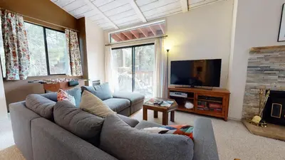 a living room with a gray couch and a tv at Mammoth Reservations in Mammoth Lakes