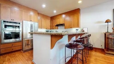 a kitchen with wooden cabinets and a counter with bar stools at Timbers 18 Apartment in Mammoth Lakes