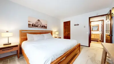 a bedroom with a large white bed and a table at Wild Flower 37 Apartment in Mammoth Lakes