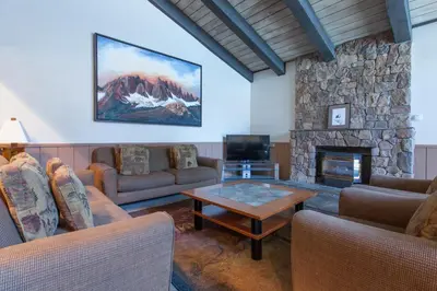 a living room with couches and a stone fireplace at Chamonix # 88 in Mammoth Lakes