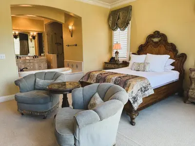 a bedroom with a large bed and two chairs at Villa Arden Hills in Sacramento