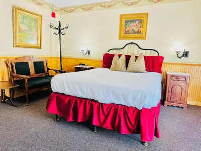 a bedroom with a large bed and a chair at Gunn House Hotel in Sonora
