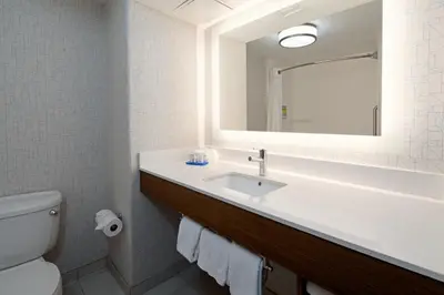 a bathroom with a sink and a mirror and a toilet at Holiday Inn Express Fresno South by IHG in Fresno