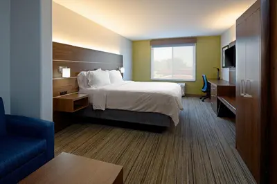 a hotel room with a bed and a blue chair at Holiday Inn Express Fresno South by IHG in Fresno