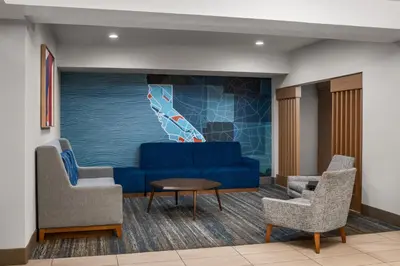 a waiting room with a blue couch and two chairs at Holiday Inn Express Fresno River Park Highway 41 by IHG in Fresno