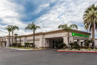 a convenience store with palm trees in a parking lot at Wyndham Garden Fresno Yosemite Airport in Fresno