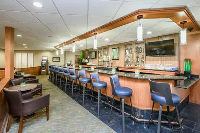 a bar in a restaurant with blue stools at Wyndham Garden Fresno Yosemite Airport in Fresno