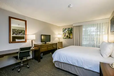 a hotel room with a bed and a desk and a computer at Wyndham Garden Fresno Yosemite Airport in Fresno