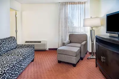 a living room with a couch and a chair and a tv at Wyndham Sacramento in Sacramento