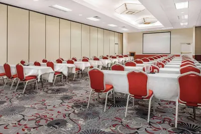 a conference room with tables and chairs and a screen at Wyndham Sacramento in Sacramento