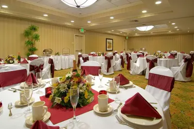a banquet hall with white tables and red chairs at Hilton Garden Inn Sacramento Elk Grove in Elk Grove