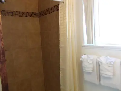 a bathroom with a shower with towels and a window at Alpine Inn & Spa in South Lake Tahoe