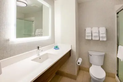a bathroom with a sink and a toilet and a mirror at Holiday Inn Express & Suites Yosemite Park Area by IHG in Chowchilla