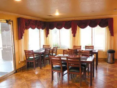 a dining room with tables and chairs and windows at Americas Best Value Inn Hanford in Hanford