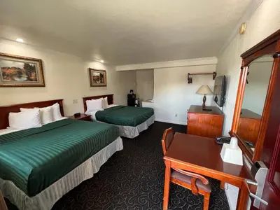 a hotel room with two beds and a desk at Americas Best Value Inn Hanford in Hanford