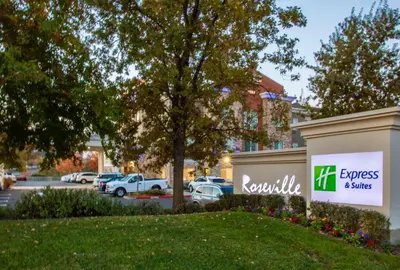 a sign in front of a parking lot at Holiday Inn Express Hotel & Suites Roseville - Galleria Area by IHG in Roseville