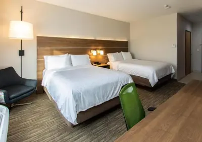 a hotel room with two beds and a chair at Holiday Inn Express Hotel & Suites Roseville - Galleria Area by IHG in Roseville