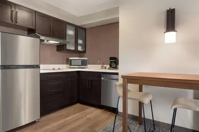 a kitchen with a refrigerator and a table with chairs at Residence Inn by Marriott Roseville in Roseville