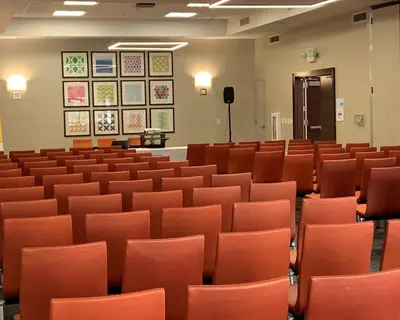 an empty lecture hall with orange chairs and pictures on the wall at Holiday Inn Express Hotel & Suites El Dorado Hills by IHG in El Dorado Hills