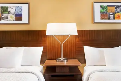 two beds in a hotel room with a lamp between them at Fairfield Inn by Marriott Roseville in Roseville