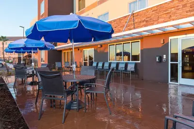 a patio with tables and chairs with blue umbrellas at Fairfield Inn & Suites by Marriott Sacramento Folsom in Folsom