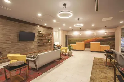 a lobby with a wall with a tv and chairs at La Quinta by Wyndham Morgan Hill-San Jose South in Morgan Hill